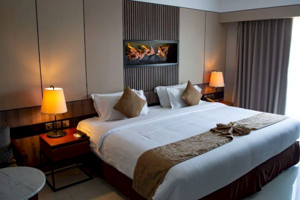 A stylish hotel room features a large bed, bedside tables with lamps, and wall decor, creating a cozy and inviting atmosphere.