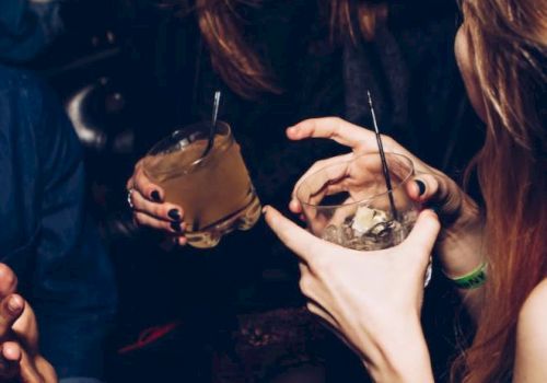 People are sitting and holding drinks, with one person laughing and others engaging in conversation in a social setting.