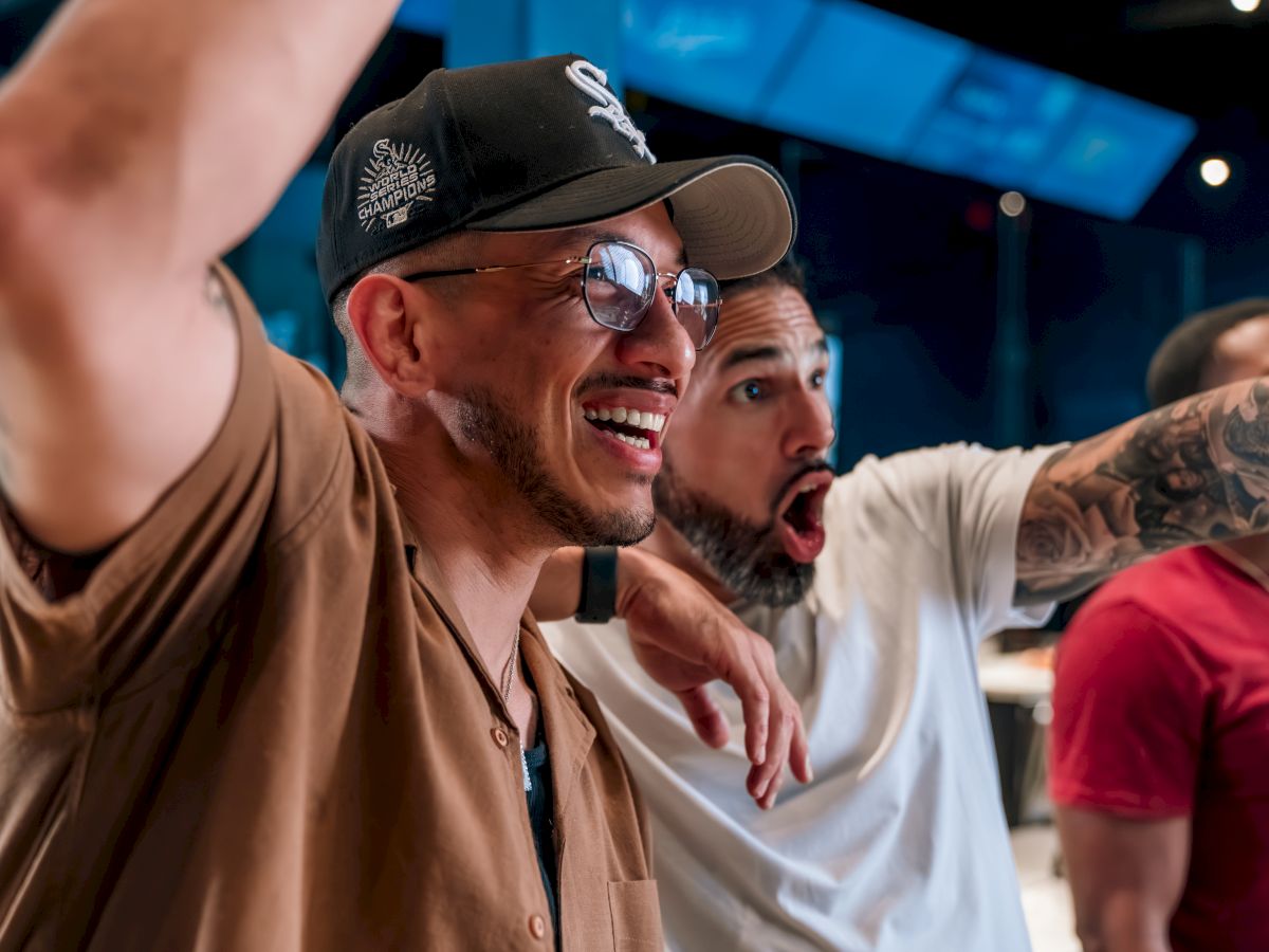 Two people are enjoying a lively moment, with one smiling broadly and the other looking surprised, in a casual setting.