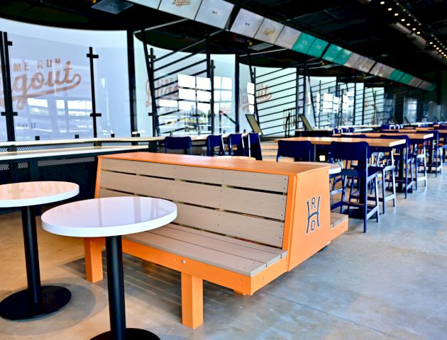The image shows a modern dining area with tables, chairs, and benches. A "Home Run Dugout" sign is visible through the windows.