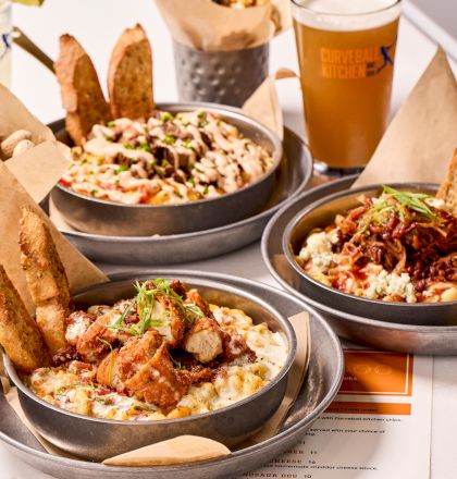 Plates of various dishes with bread, a pint of beer, and a menu on the table.