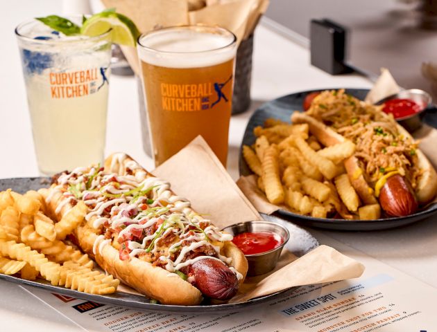 Two plates with hot dogs and crinkle-cut fries, plus drinks on a table.