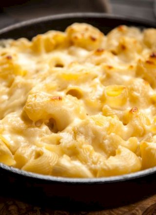 A skillet filled with creamy baked macaroni and cheese, topped with a golden, melted cheese crust.