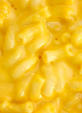 The image shows a close-up of creamy macaroni and cheese, showcasing the pasta and the rich, yellow cheese sauce.